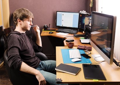 Freelance developer and designer working at home, man using desktop computer.