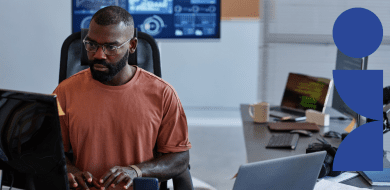 Un homme concentré travaillant sur un ordinateur dans un bureau moderne, avec des écrans affichant des données numériques en arrière-plan, illustrant le métier de développeur no code.