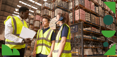 Trois professionnels en gilet de sécurité échangent dans un entrepôt, illustrant le rôle du responsable QHSE dans la gestion de la sécurité et de la qualité au travail.