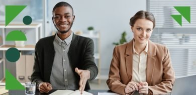 Deux responsables des ressources humaines assis à un bureau, souriants, accueillant un candidat en entretien. L’un d’eux tend la main pour saluer, symbolisant un échange professionnel et bienveillant.