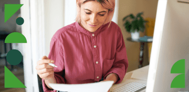Une personne travaille à son bureau, examinant des documents devant un ordinateur, dans un environnement lumineux et professionnel.